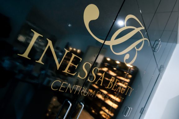 Schriftzug "INESSA BEAUTY CENTER" in gold auf dunklem Hintergrund.